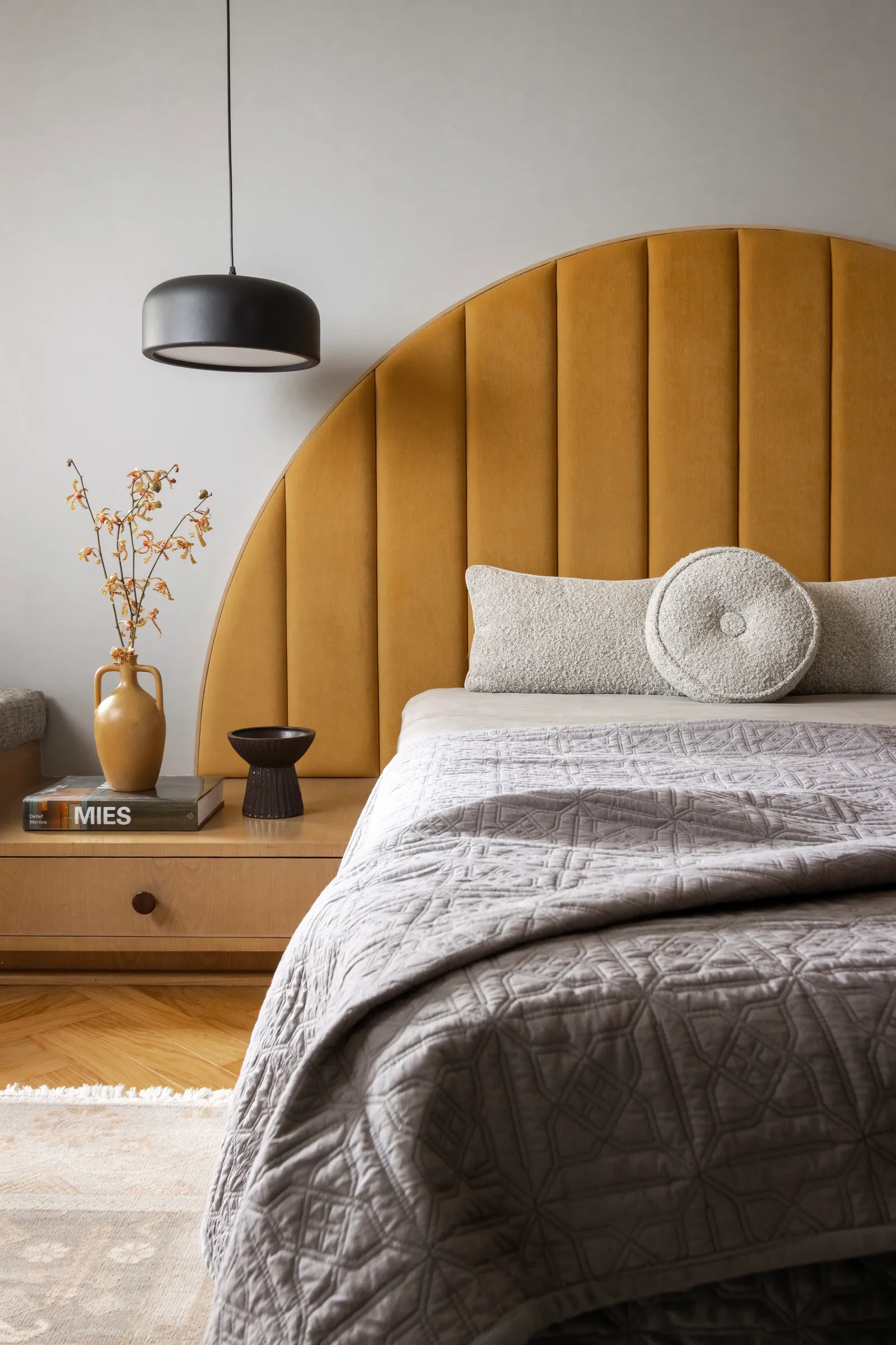 The primary bedroom, crowned by a mustard arched headboard