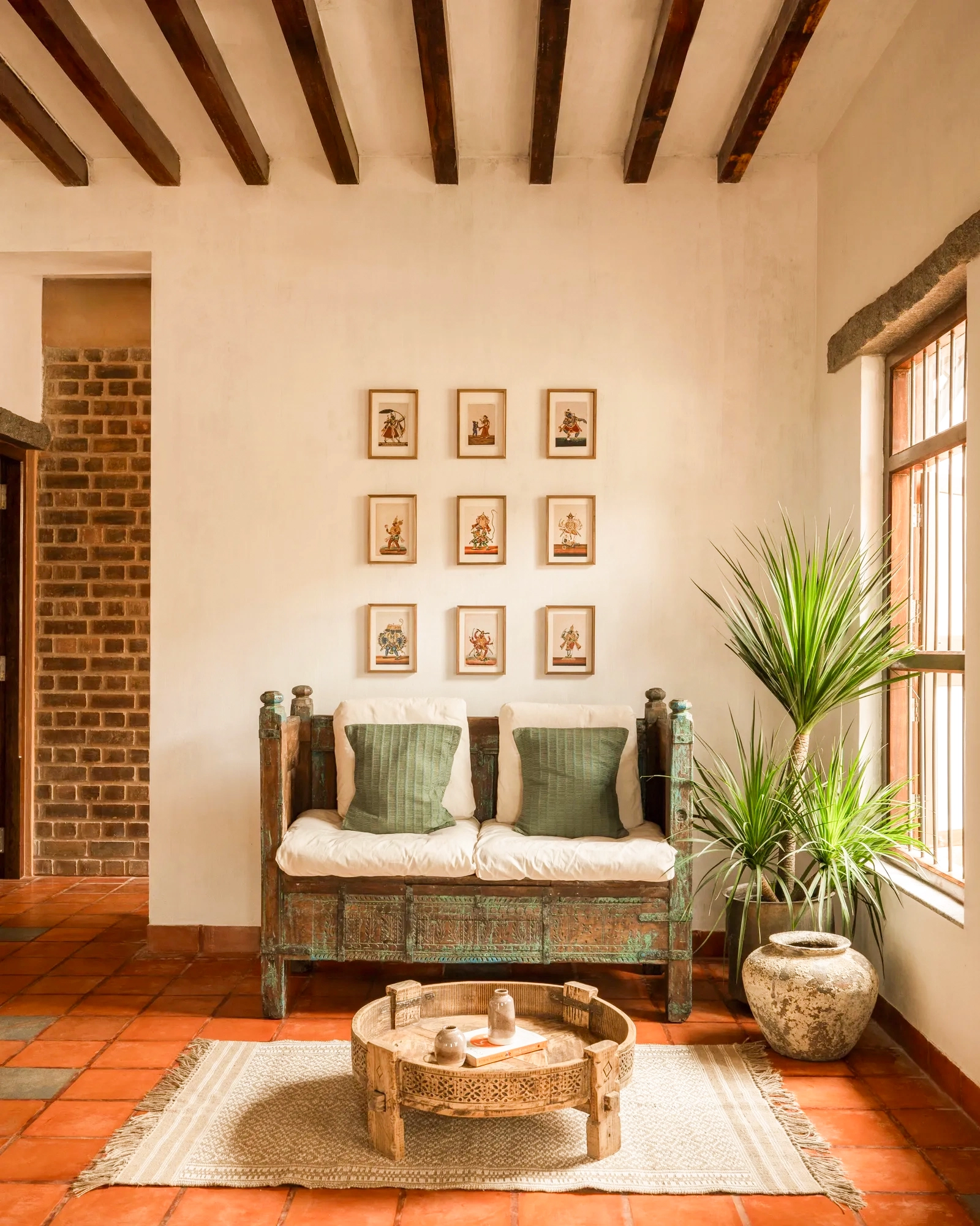 The living room — terracotta floors, framed miniatures and handcrafted furniture