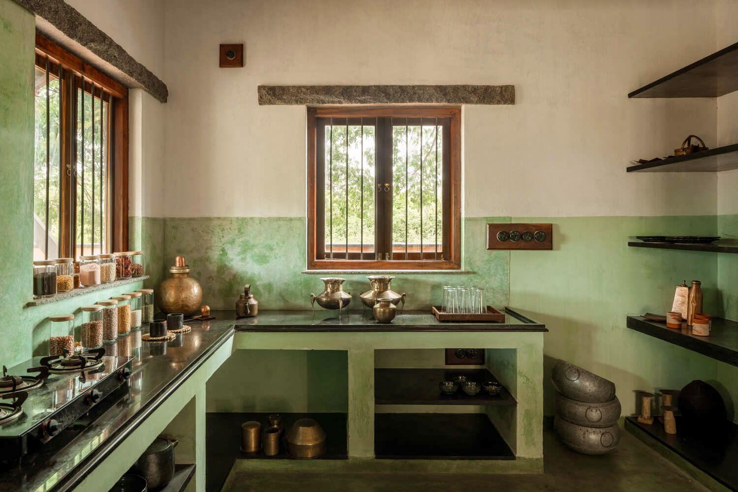 The kitchen in oxide green, lined with brass and stone