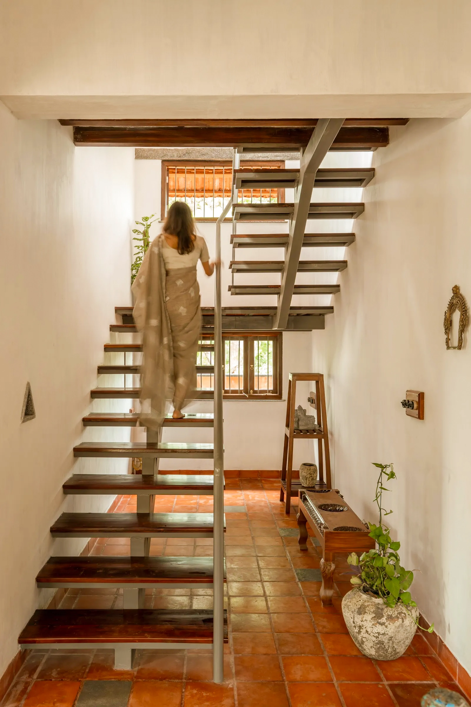 A sculptural timber staircase over terracotta